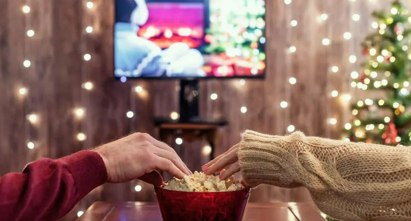 Christmas eve. Couple watching tv and eating popcorn. Home cinema. Cropped, close up