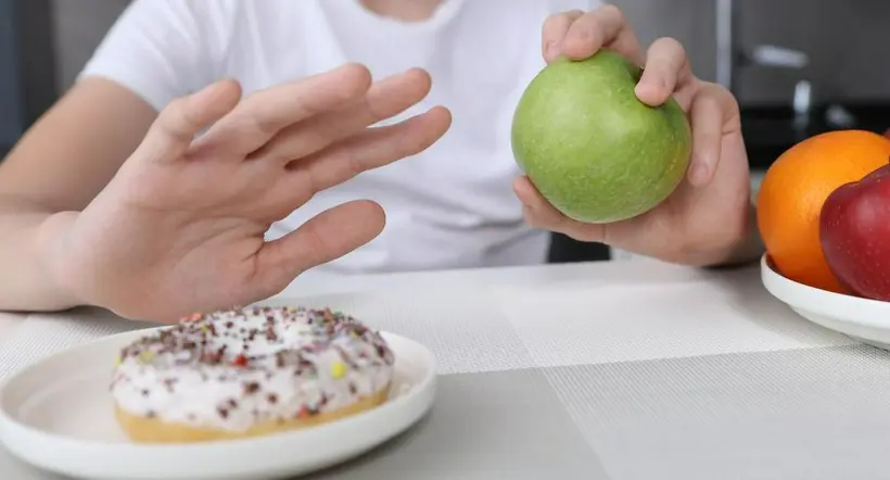 Persona eligiendo una fruta antes que una golosina a propósito de cómo limpiar el hígado en tres días.