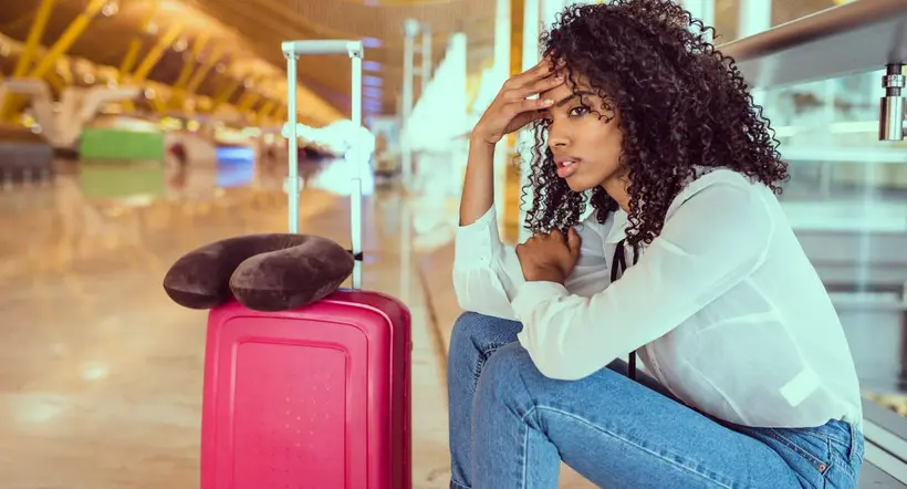 Mujer preocupada con una maleta en un aeropuerto.