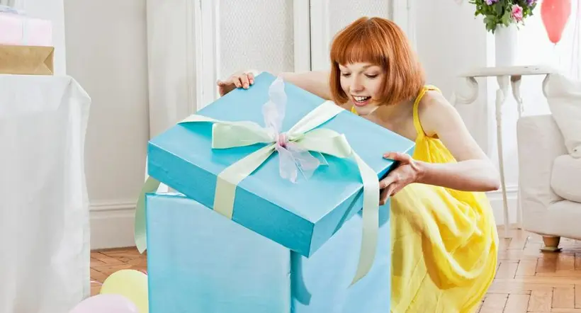 Mujer destapando un regalo a propósito de algunas ideas originales que puede regalar en el Día Internacional de la Mujer.