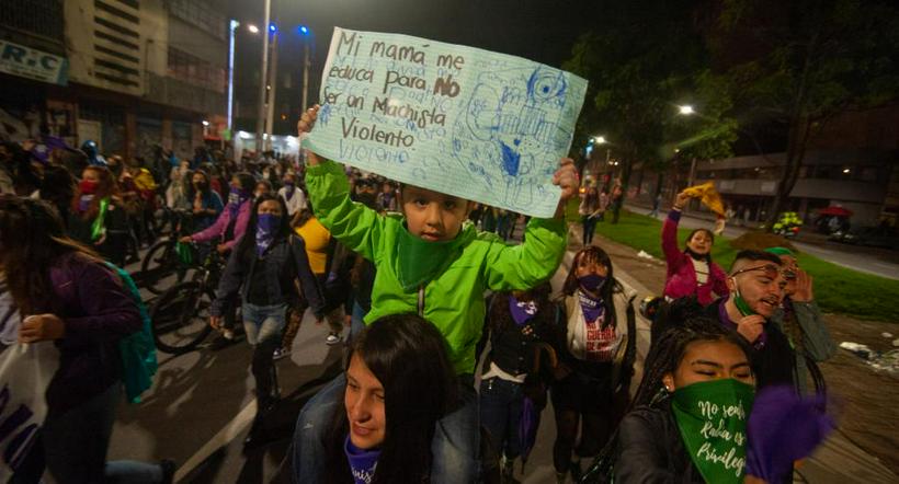 Niño sostiene un cartel en medio de una marcha feminista a propósito de las movilizaciones del 8 de marzo.