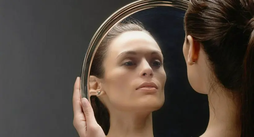 Persona mirándose en un espejo a propósito de la definición de la palabra narcisista y por qué se usa tanto en redes sociales.