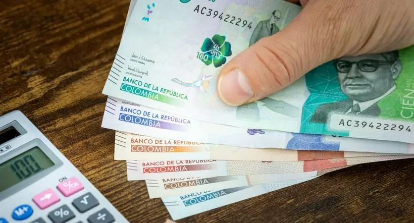 Man holds Colombian pesos in hand and counts on expenses or earnings calculator, Financial concept, home budget of Colombians