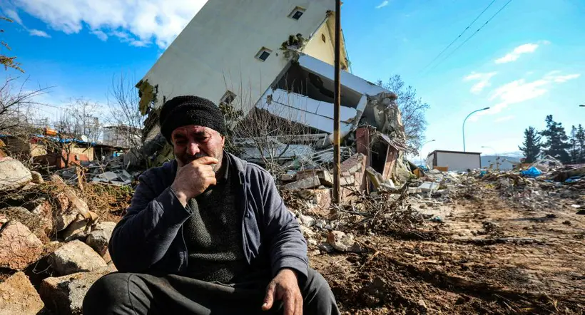 Un hombre sentado sobre escombros del terremoto en Turquía.