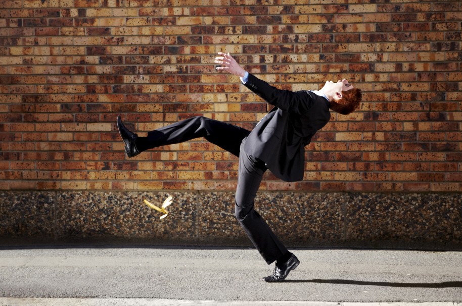 A young businessman falling after stepping on a banana peel