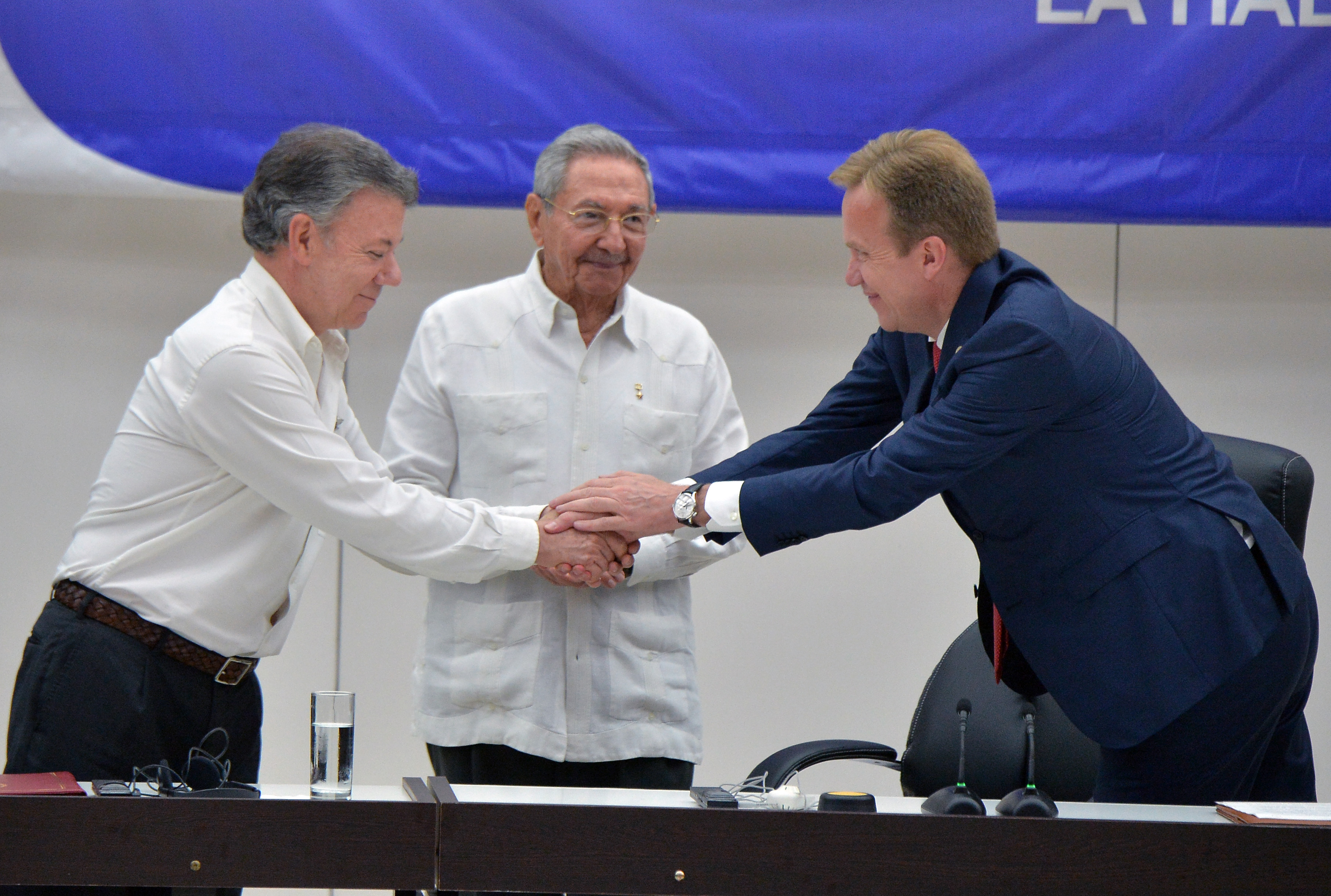 Colombia's President Juan Manuel Santos (L) shakes hands with Norway's Foreign Minister Borge Brende, as Cuban President Raul Castro (C) looks on during the signing of the ceasefire between the Colombian government and the FARC guerrilla, in Havana on June 23, 2016. Colombia's government and the FARC guerrilla force signed a definitive ceasefire Thursday, taking one of the last crucial steps toward ending Latin America's longest civil war. / AFP PHOTO / ADALBERTO ROQUE