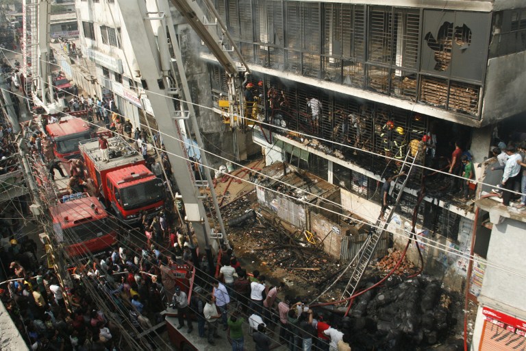 Bangladeshi firefighters stand in a burned out bulding as they try and control a fire that broke out at a garment factory on the outskirts of Dhaka on November 26, 2012. Bangladesh firefighters quelled a new blaze at a garment factory as the country mourned the death of 110 workers in a weekend blaze at an apparel plant, the export industry's worst-ever accident. The latest fire caused widespread damage at the plant on the outskirts of the capital Dhaka, but no casualties were reported after rescue teams searched the building for workers feared to have suffocated in toxic black fumes. AFP PHOTO/ STR / AFP PHOTO / STR