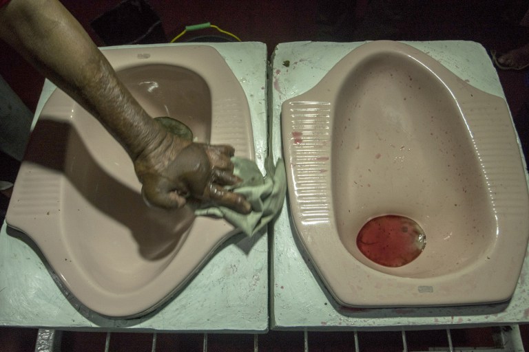 This picture taken on July 16, 2016 shows a worker cleaning up a squat toilet display from where customers ate a meal at the "Jamban Cafe" in the city of Semarang on Java island, a small eatery where a handful of diners sit on upright toilets around a table where food is served in two squat toilets. The toilet-themed cafe where customers dine on meatballs floating in soup-filled latrines may not be everyone's idea of haute cuisine, but Indonesians are flocking to become privy to the latest lavatorial trend. / AFP PHOTO / SURYO WIBOWO