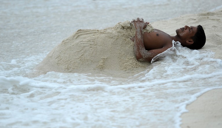 Hombre juega con la arena en Maldivas. Pulzo.com