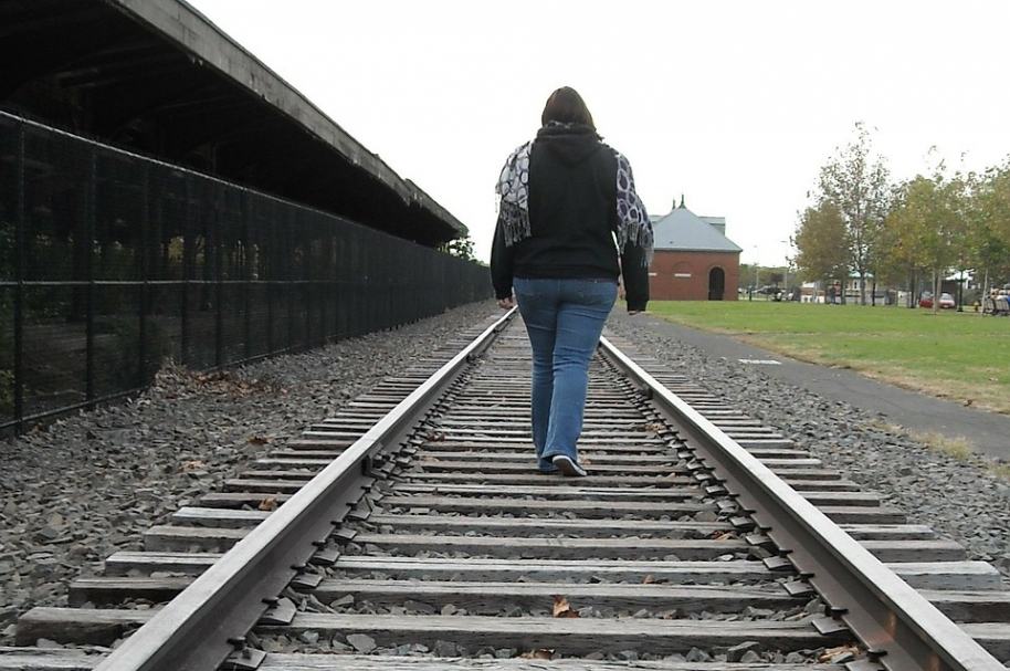 Mujer caminando por vía férrea. Pulzo.com