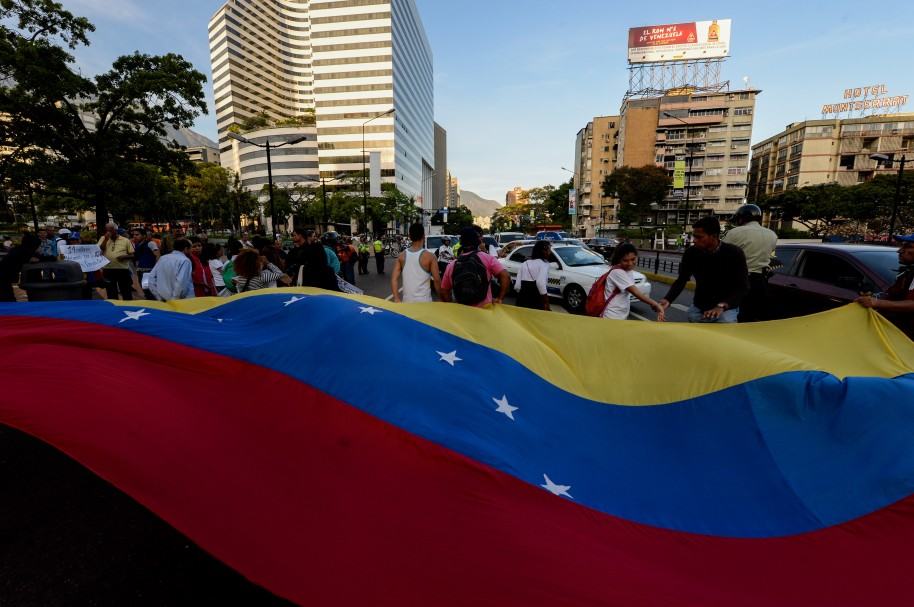 Opositores venezolanos despliegan una bandera durante marchas