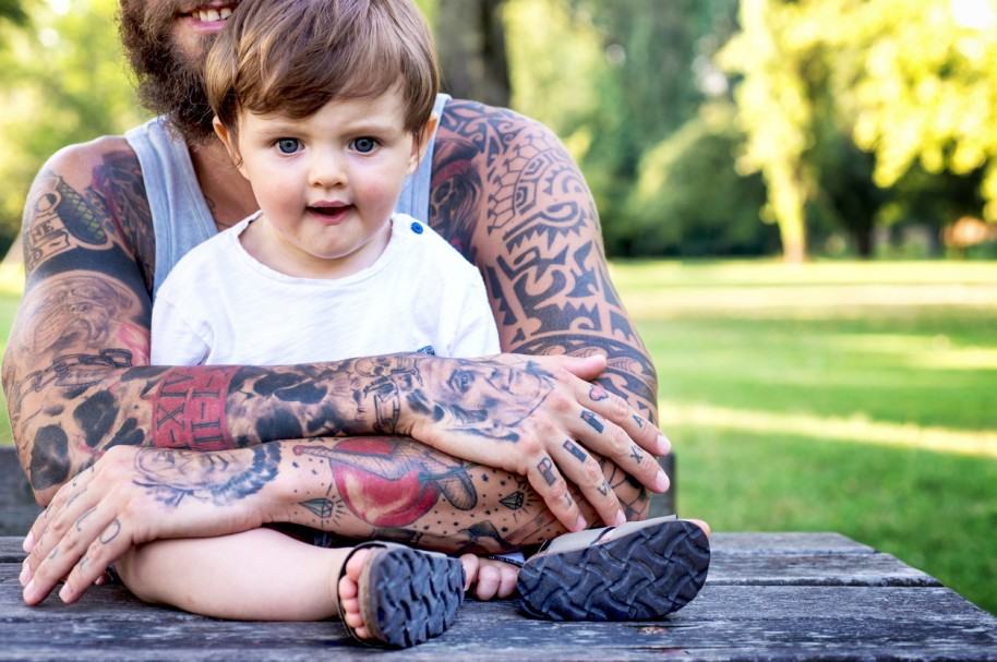 Padre tatuado abrazando a su hijo. Pulzo.com
