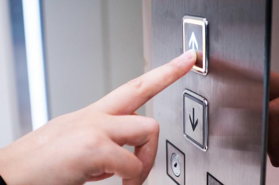 Hombre presiona botón para subir al ascensor. Pulzo.com