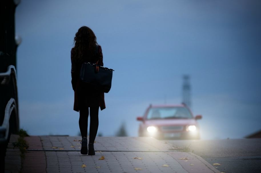 Mujer en la vía con auto de frente.