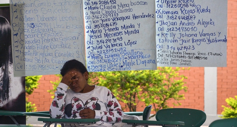 Mujer sentada delante de lista de desaparecidos