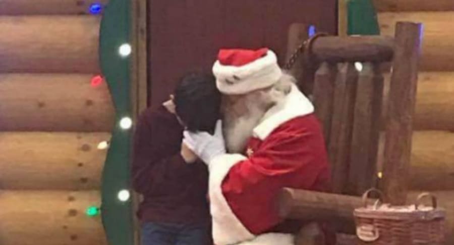 Papá Noel reza junto a niño.