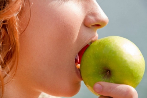 Mujer muerde manzana.