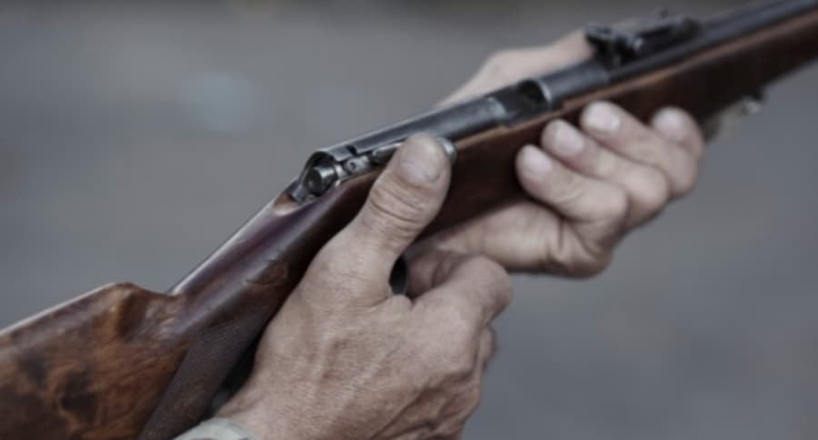 Hombre sostiene rifle.