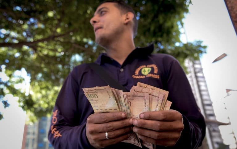 Hombre cuenta billetes de 100 bolívares