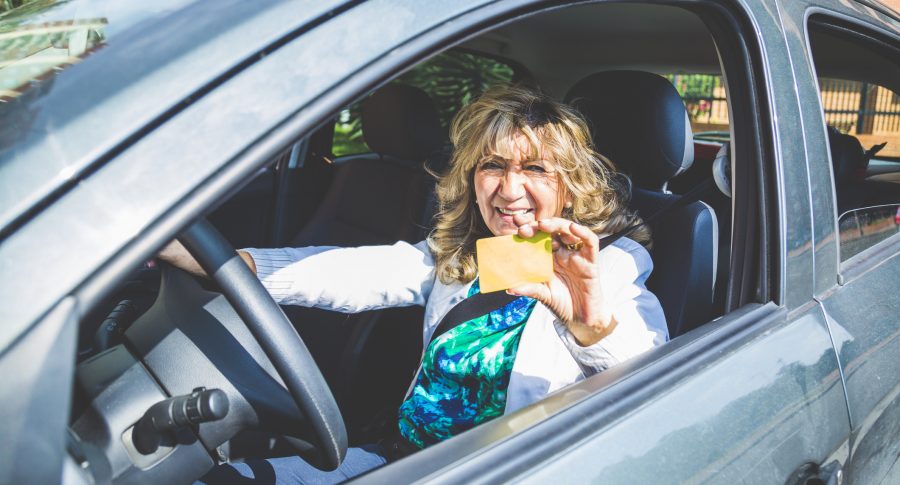 Mujer exhibiendo su licencia mientras conduce un automóvil