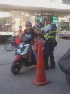 Guarda de tránsito subiendo a niño a una motocicleta