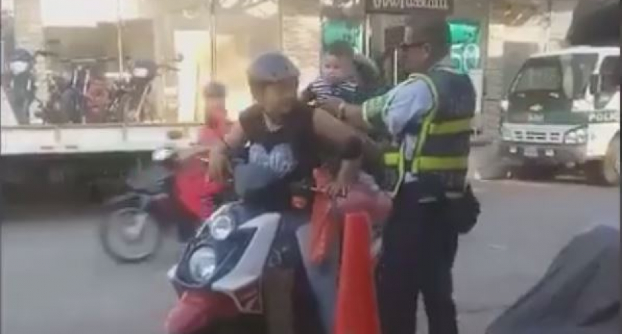 Guarda de tránsito subiendo a niño a una motocicleta