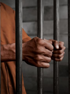 Manos de hombre agarrando barrotes de cárcel