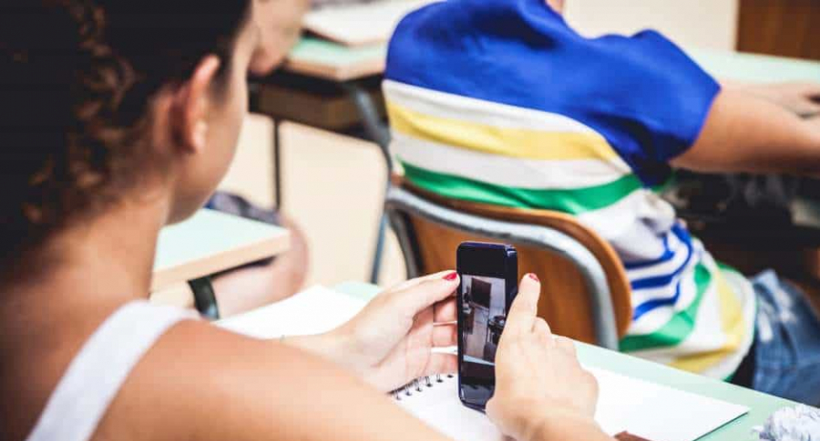 Estudiante usa celular en clase.