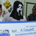 Hombre recoge premio de lotería con máscara.