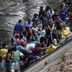 Venezolanos recogen agua de río contaminado