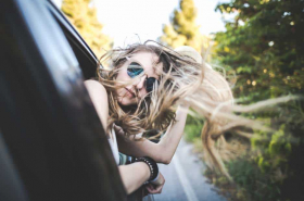 Mujer saca cabeza por ventana de carro.