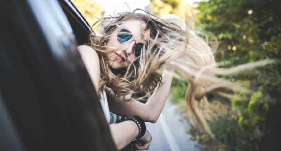 Mujer saca cabeza por ventana de carro.