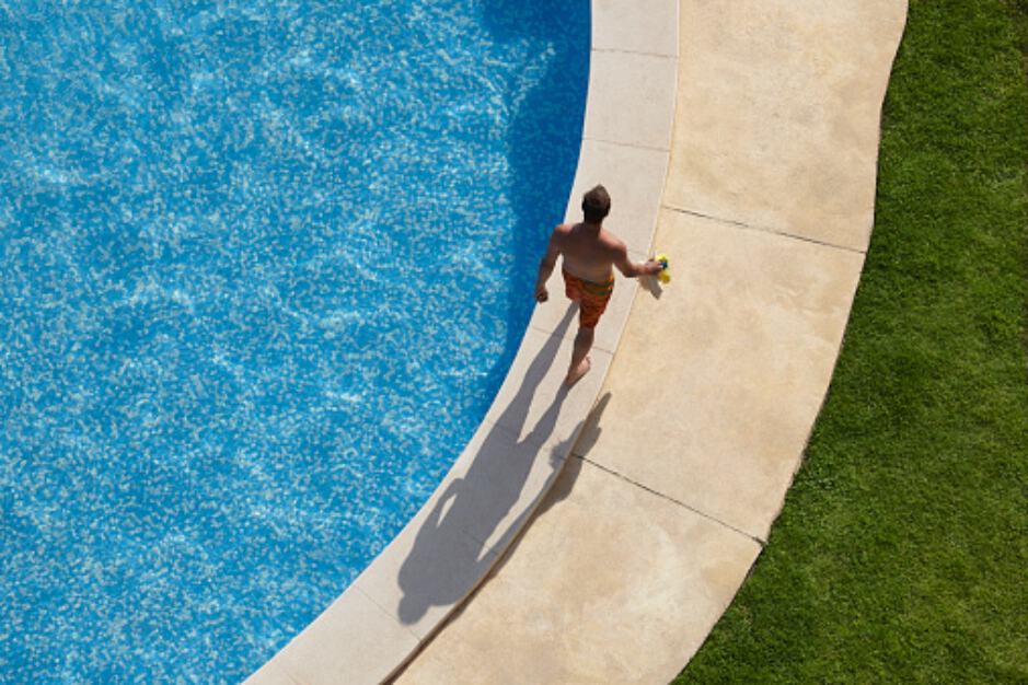 Hombre camina en borde de piscina.