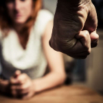Hombre empuñando su mano frente a una mujer. Maltrato a la mujer.