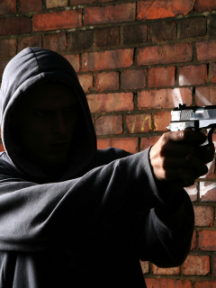 Hombre encapuchado apuntando con un arma. Imagen de referencia Getty.