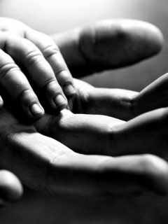 Mano de bebé sobre mano de hombre