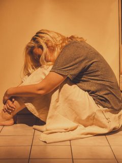 Joven en un baño acurrucada