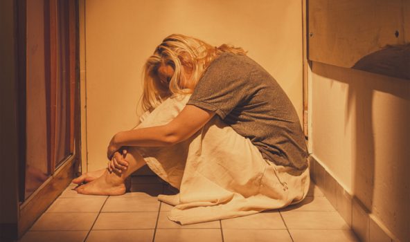 Joven en un baño acurrucada