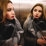 Mujer en ascensor con espejo.