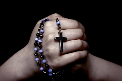 Hombre sostiene un rosario.