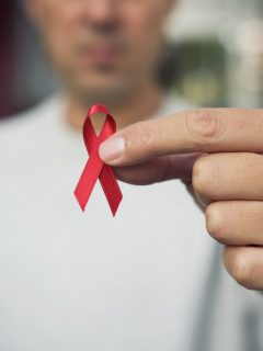 Hombre sosteniendo lazo rojo que representa el VIH