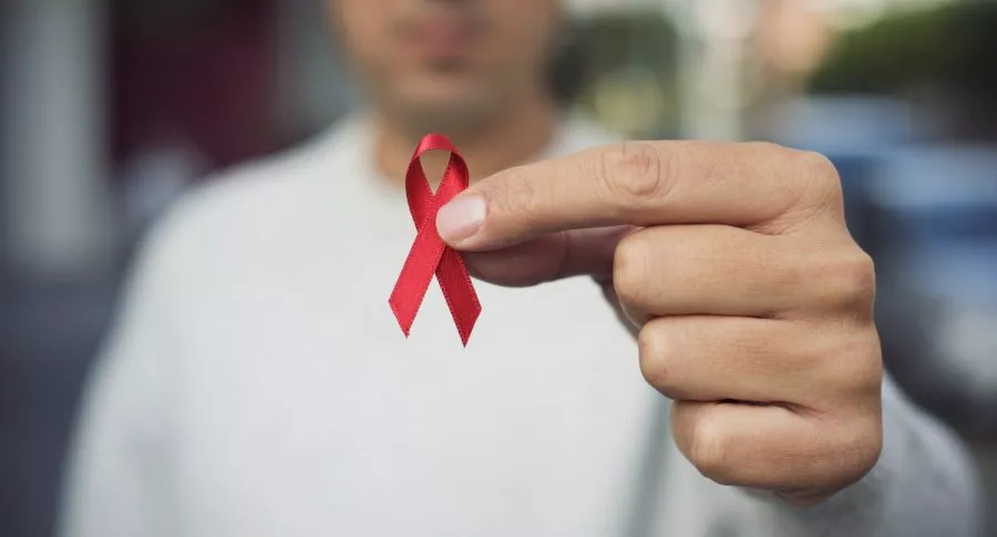 Hombre sosteniendo lazo rojo que representa el VIH