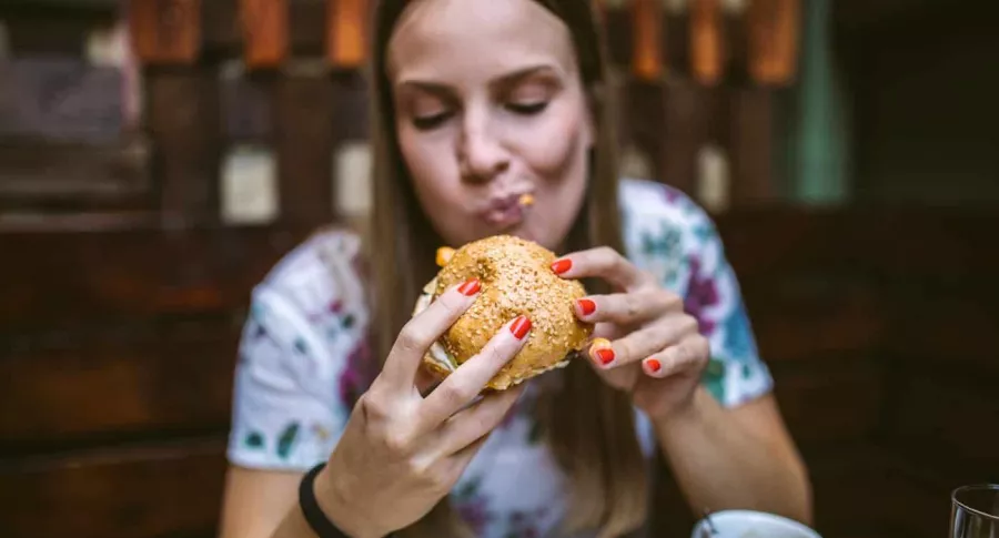 mujer comiendo hamburguesa