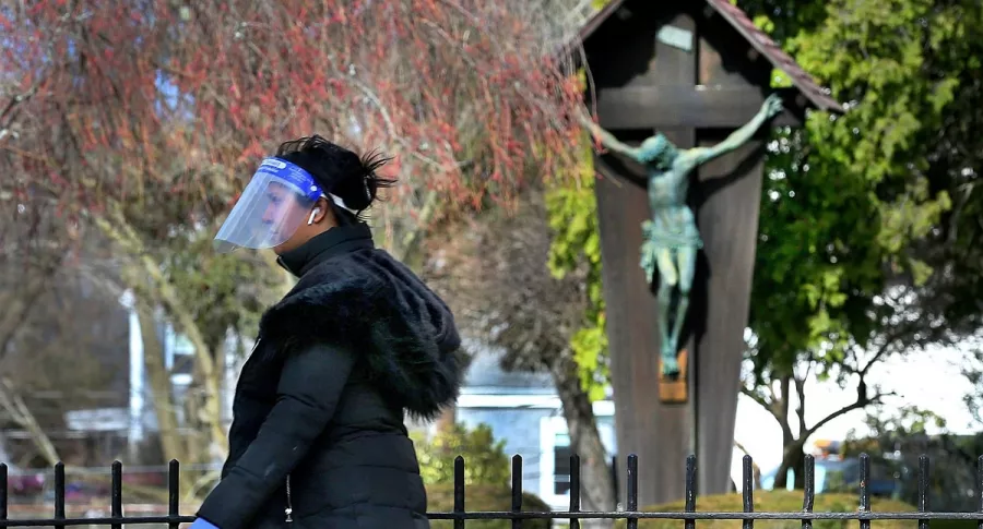 Una persona camina frente a una estatua de Cristo crucificado el Viernes Santo en Estados Unidos, durante la pandemia de COVID-19