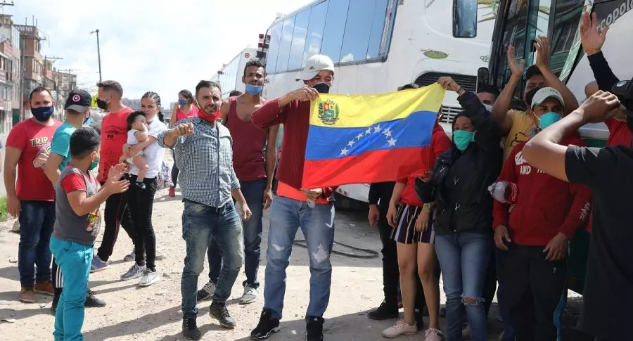 Venezolanos junto a los buses que rentaron para regresar a su país ante emergencia por COVID-19 en Colombia.