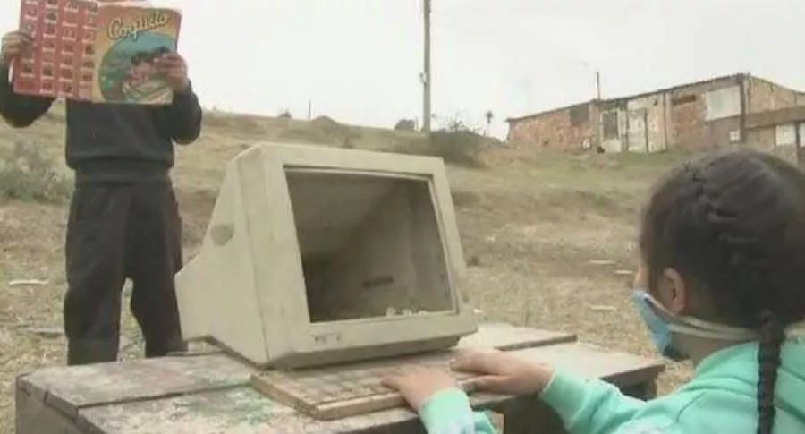 Niños jugando con computador dañado.