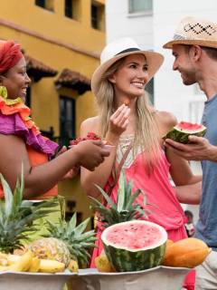 Pareja de turistas comprando frutas a una palenquera en Cartagena.