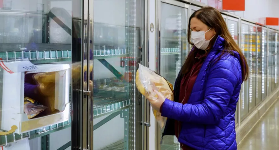 Mujer con tapabocas toma producto congelado