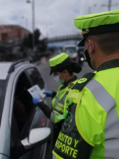 Policía revisando documentos de conductor, en Bogotá. Conozca las infracciones y las multas que pueden ponerle si incumple normas de tránsito.