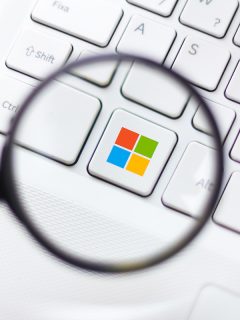 Logotipo de Microsoft bajo una lupa para ilustrar nota sobre la herramienta creada para detectar 'deepfakes'